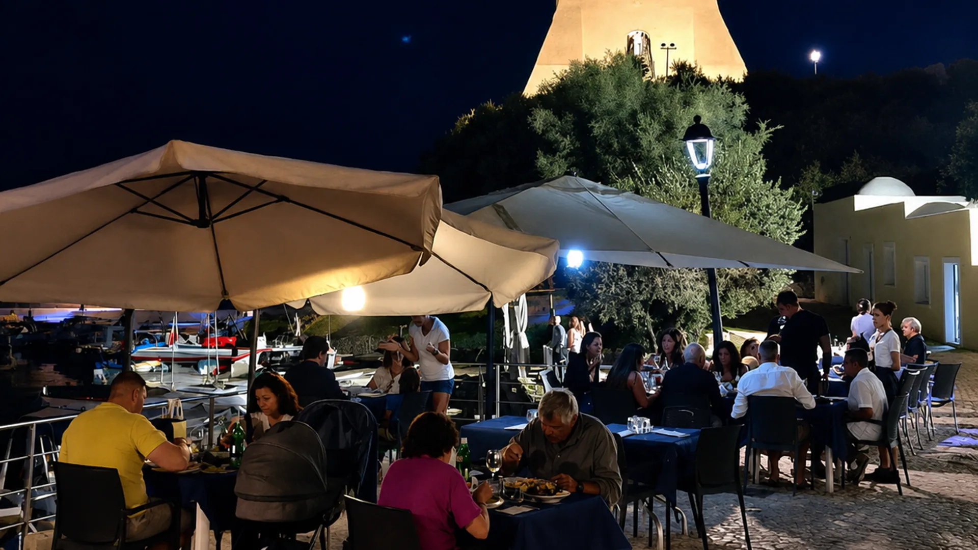 I tavoli del Porticciolo sul molo, di sera, con le luci del porto